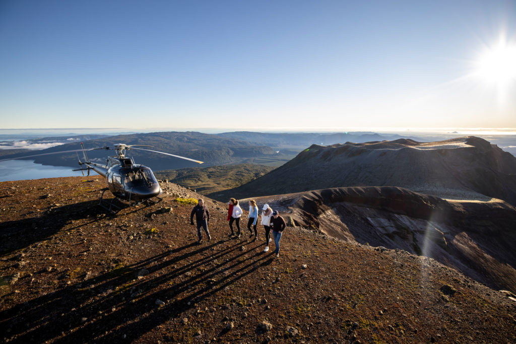 People standing on the edge of Mt Tarawera next to a helicopter