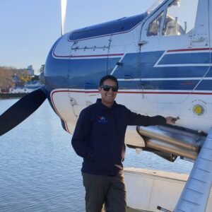 Man posing next to front of DHC floatplane